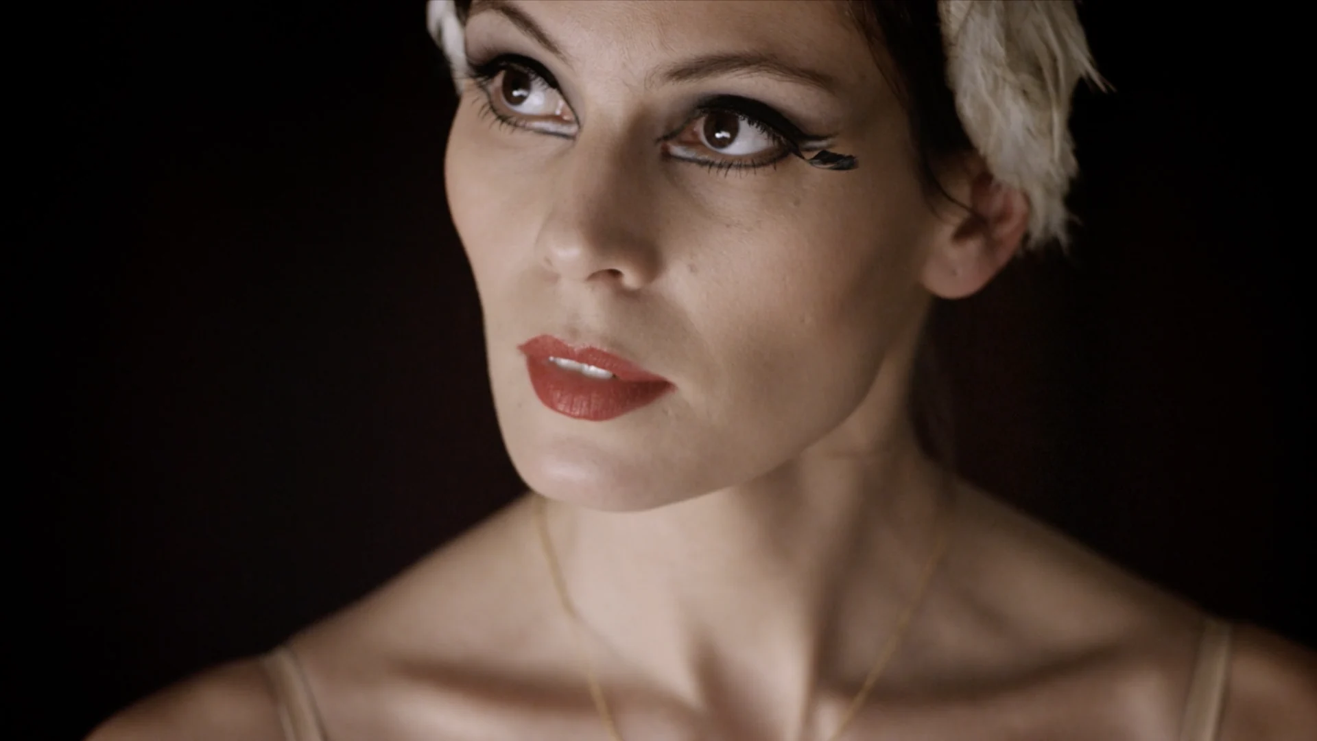 Close up of Igone de Jongh with red lips and a feathered headdress