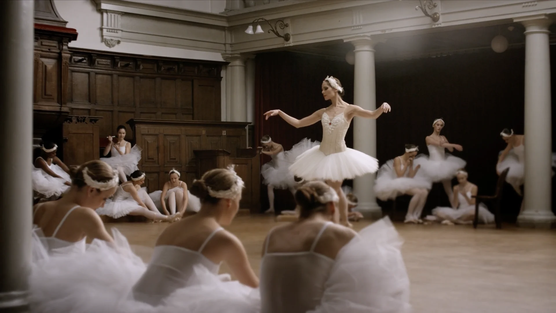 Igone de Jongh dances in a wood panelled hall while the corps de ballet rests on the floor