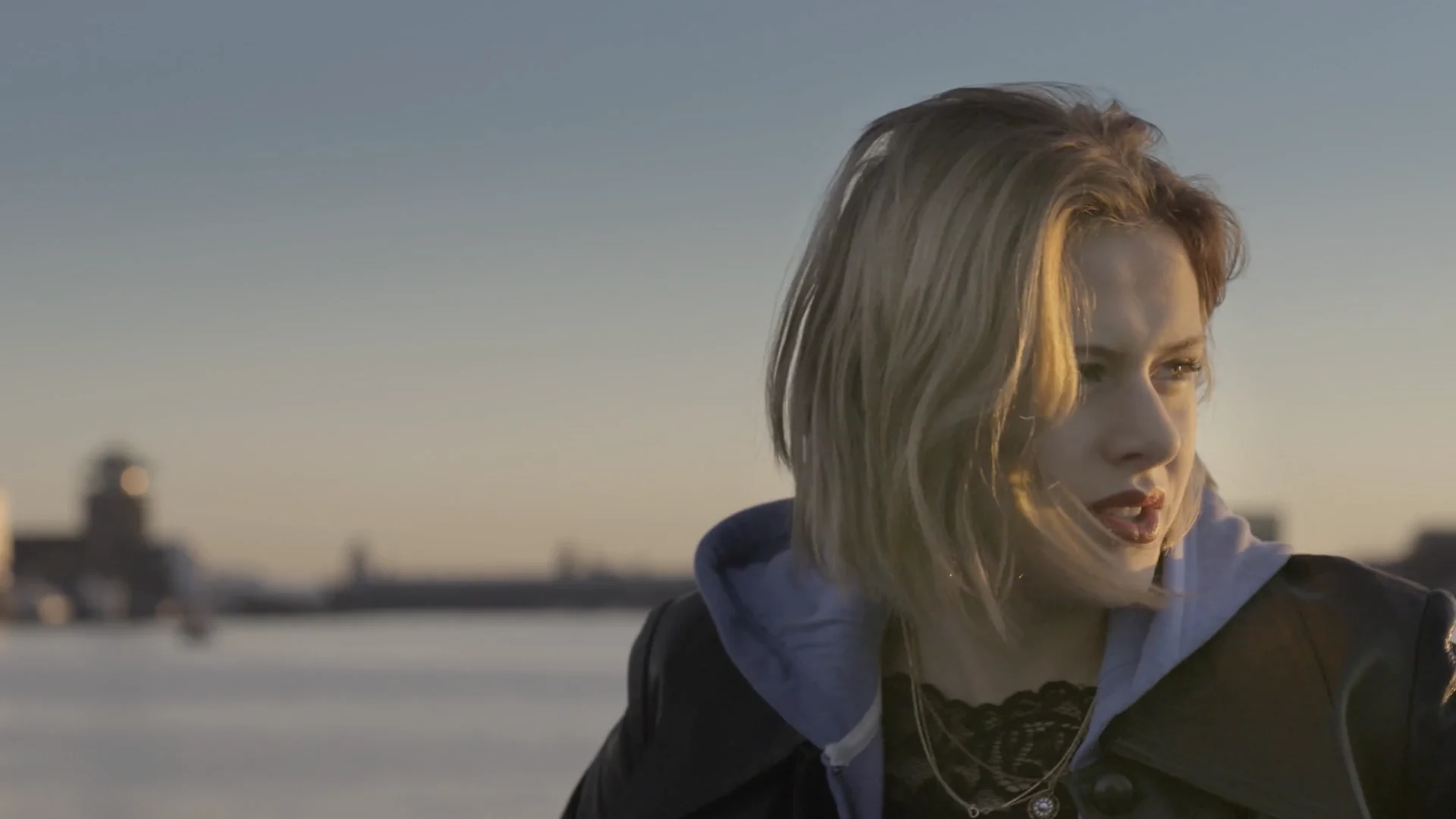 Susan Radder by the water at sunset, her hair in the wind
