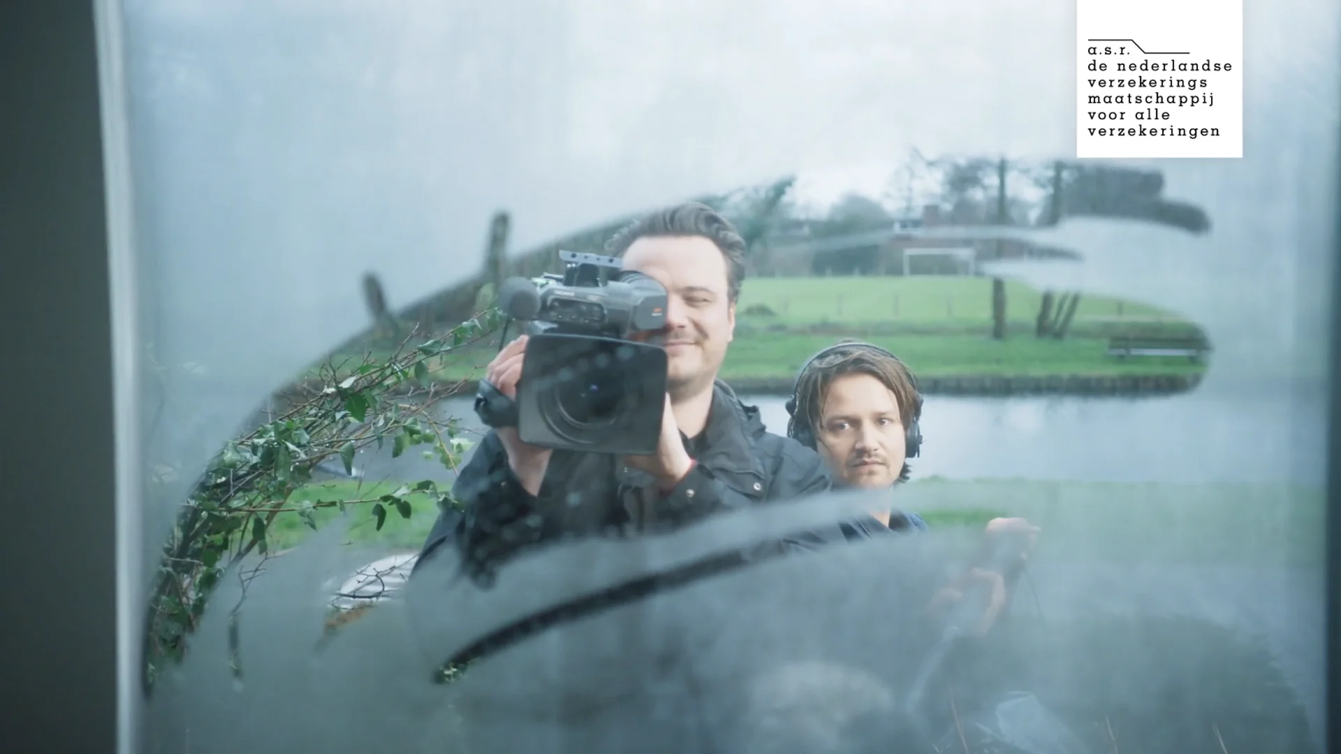 A cameraman and a sound engineer seen through a fogged window