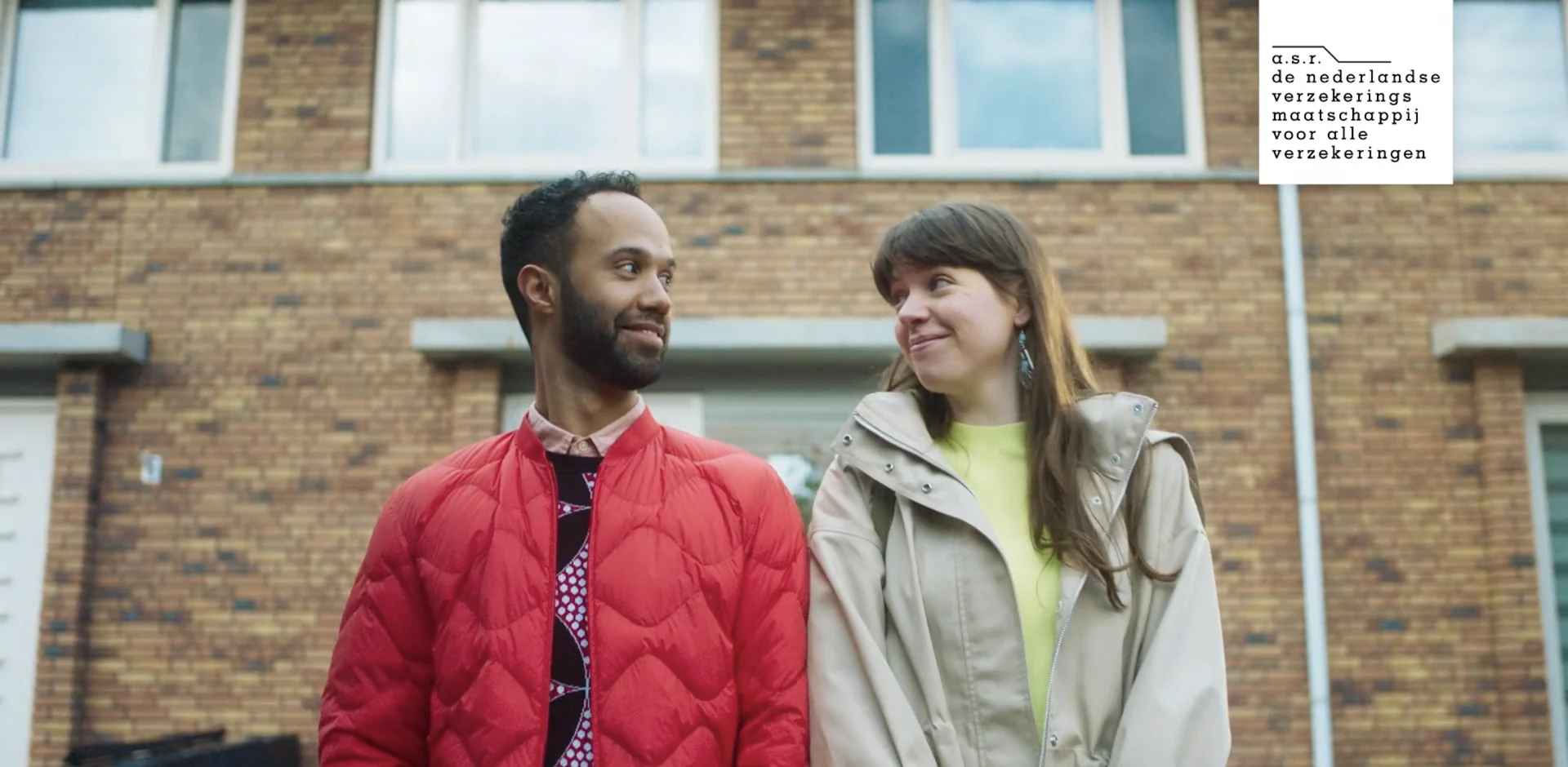 A smiling couple in front of their brick house