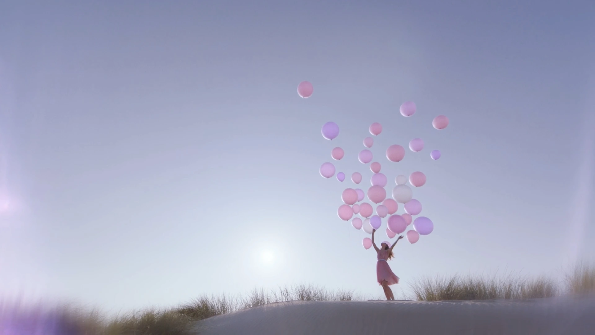A woman with a cloud of pink balloons on top of a dune in Schoorl, from the Betty Barclay Dream Away commercial