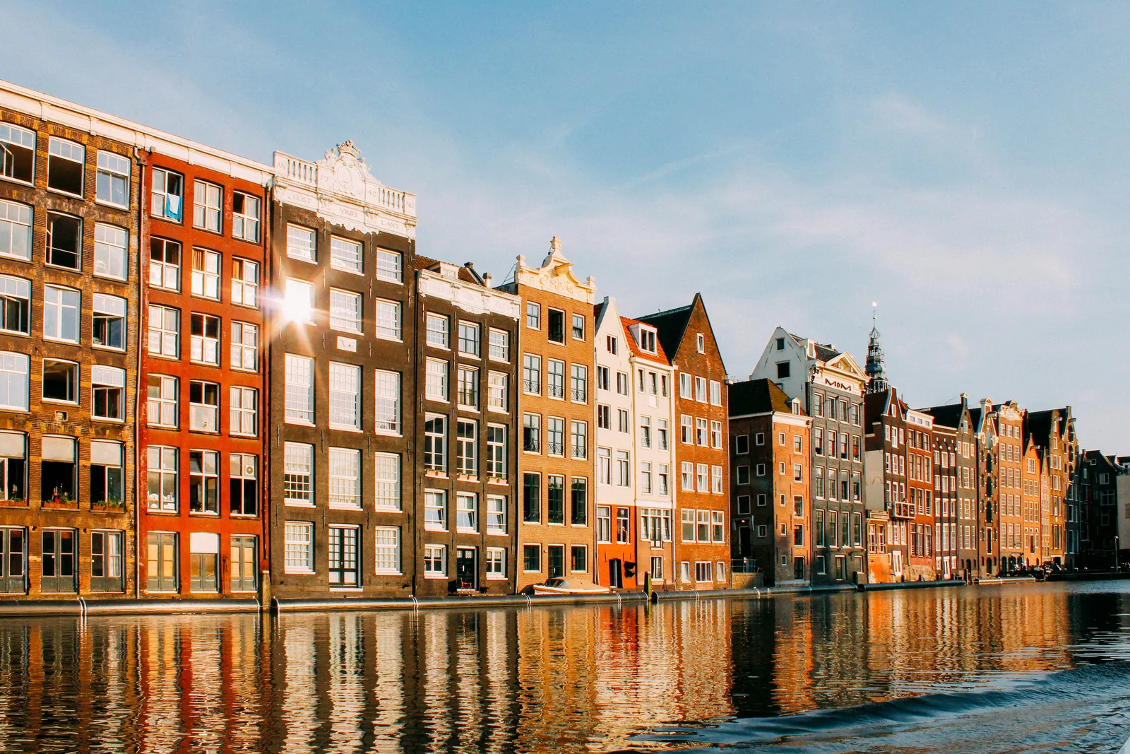 Canal houses on the Damrak in evening sun, reflected in the water