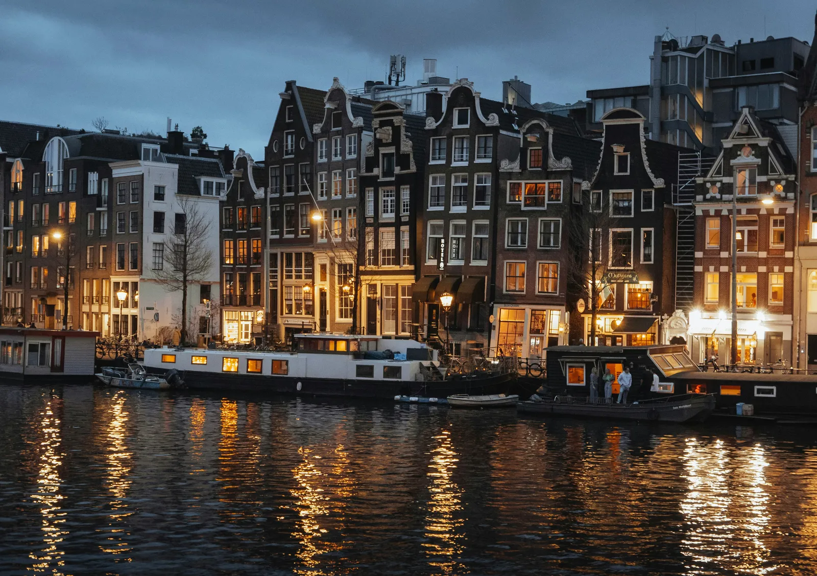 Canal houses with lit windows and houseboats at dusk