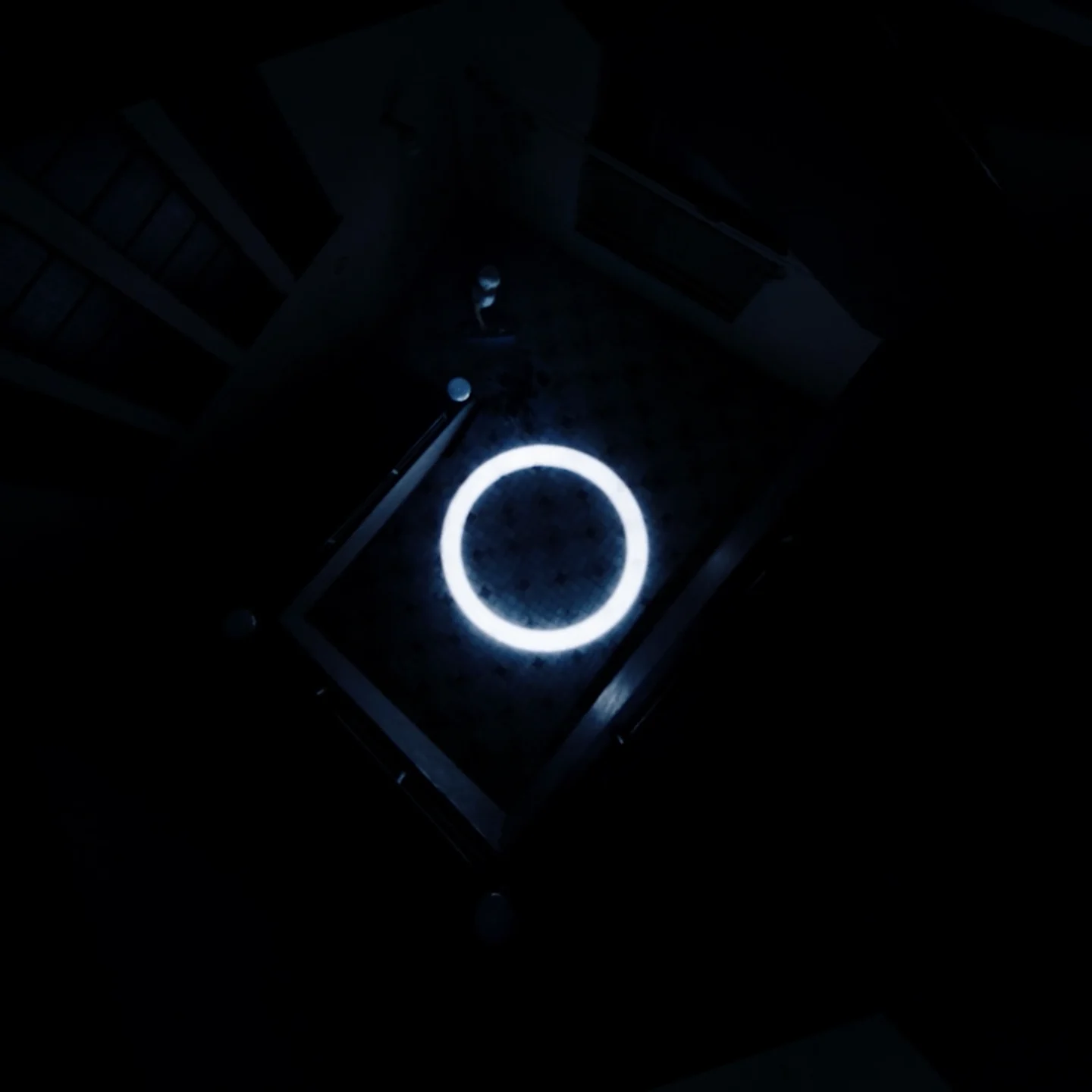 Looking down the dark stairwell at a glowing ring of light