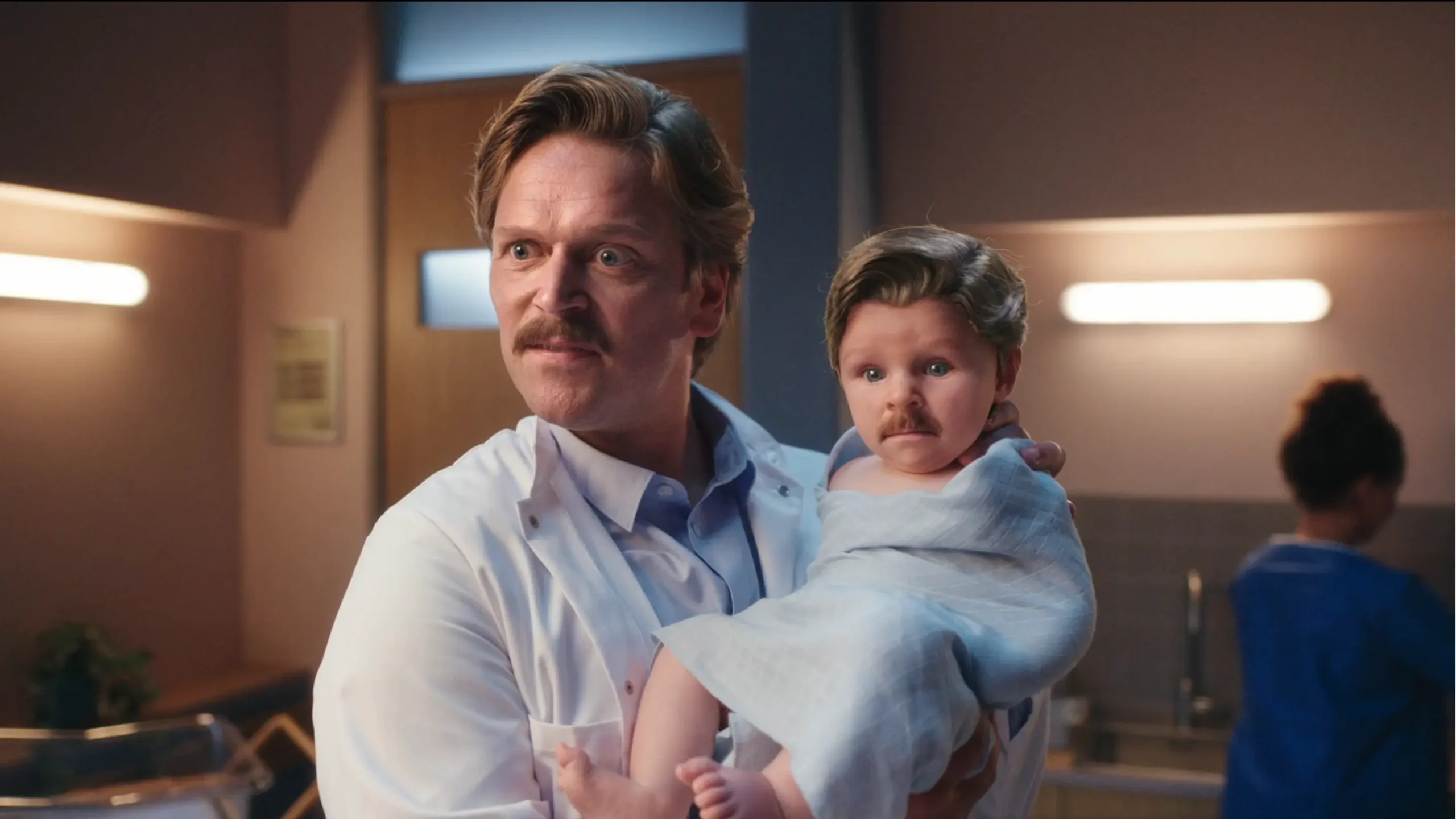 Jürgen Vogel holding a baby in the Domino Dreams campaign