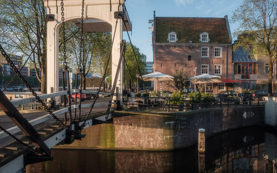A drawbridge over a canal next to a café terrace