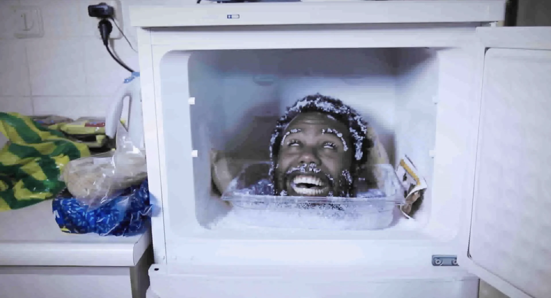 A man grins with his head inside a frosty freezer