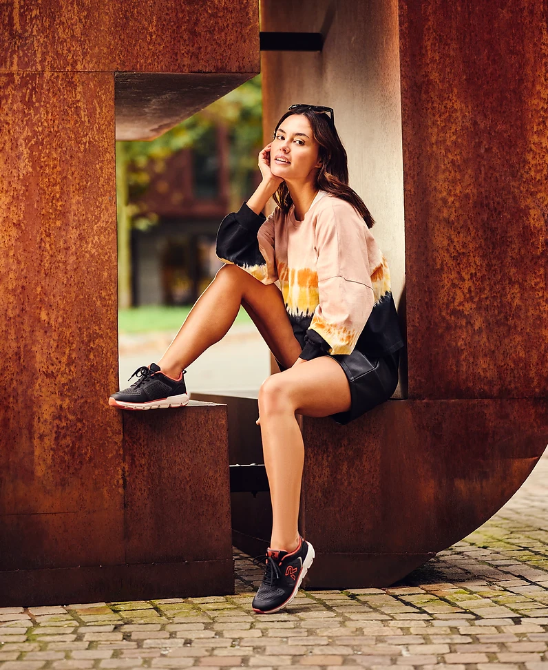 Model in Rieker sneakers sitting in a rusted steel sculpture in Eindhoven city centre