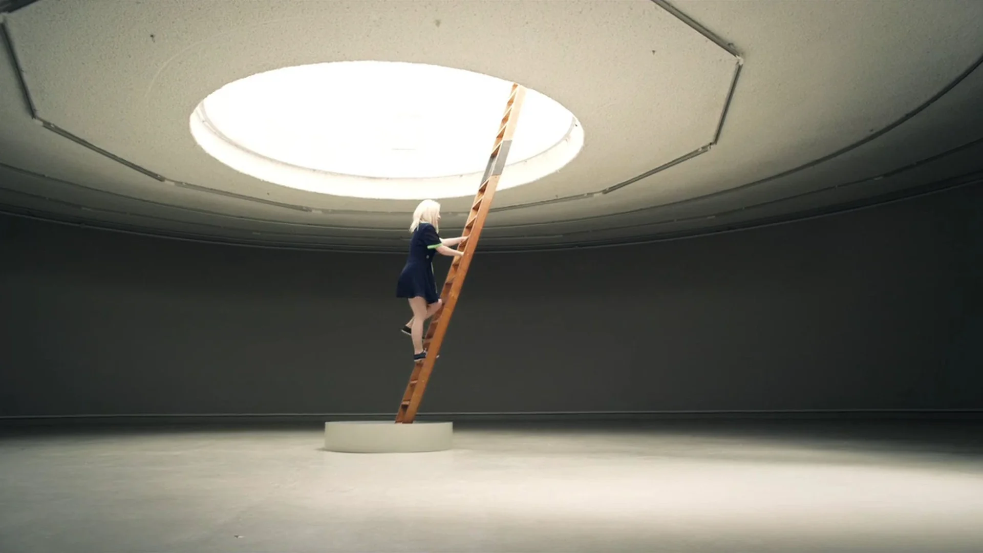 Kate Miller-Heidke climbs a ladder towards a round skylight in The Book of Sand