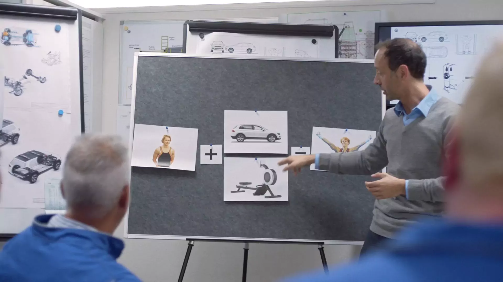 An engineer points at a board that adds Epke, the Tiguan and a rowing machine together
