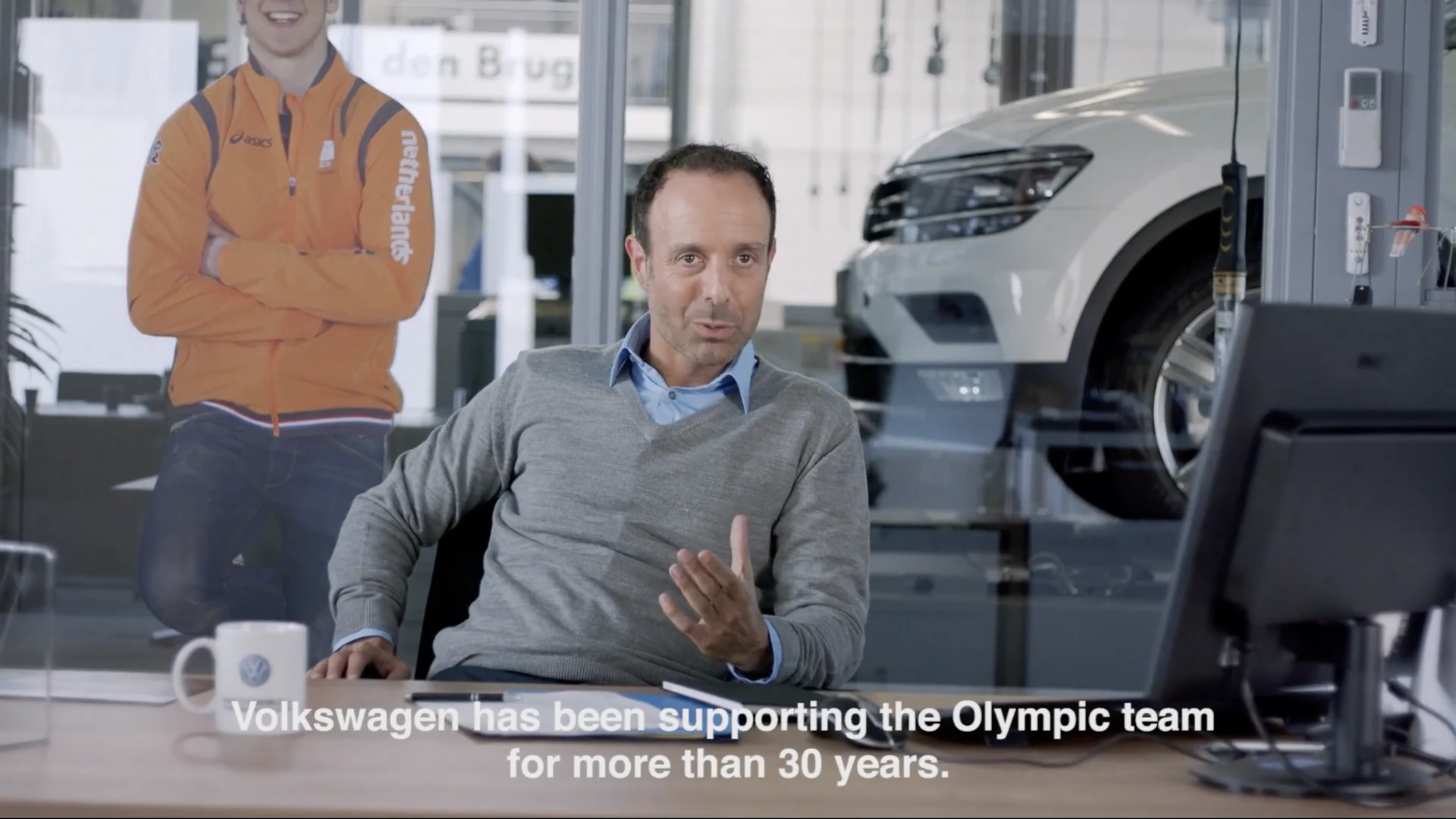 A Volkswagen engineer talks at his desk in the workshop with a cut out of Epke behind him