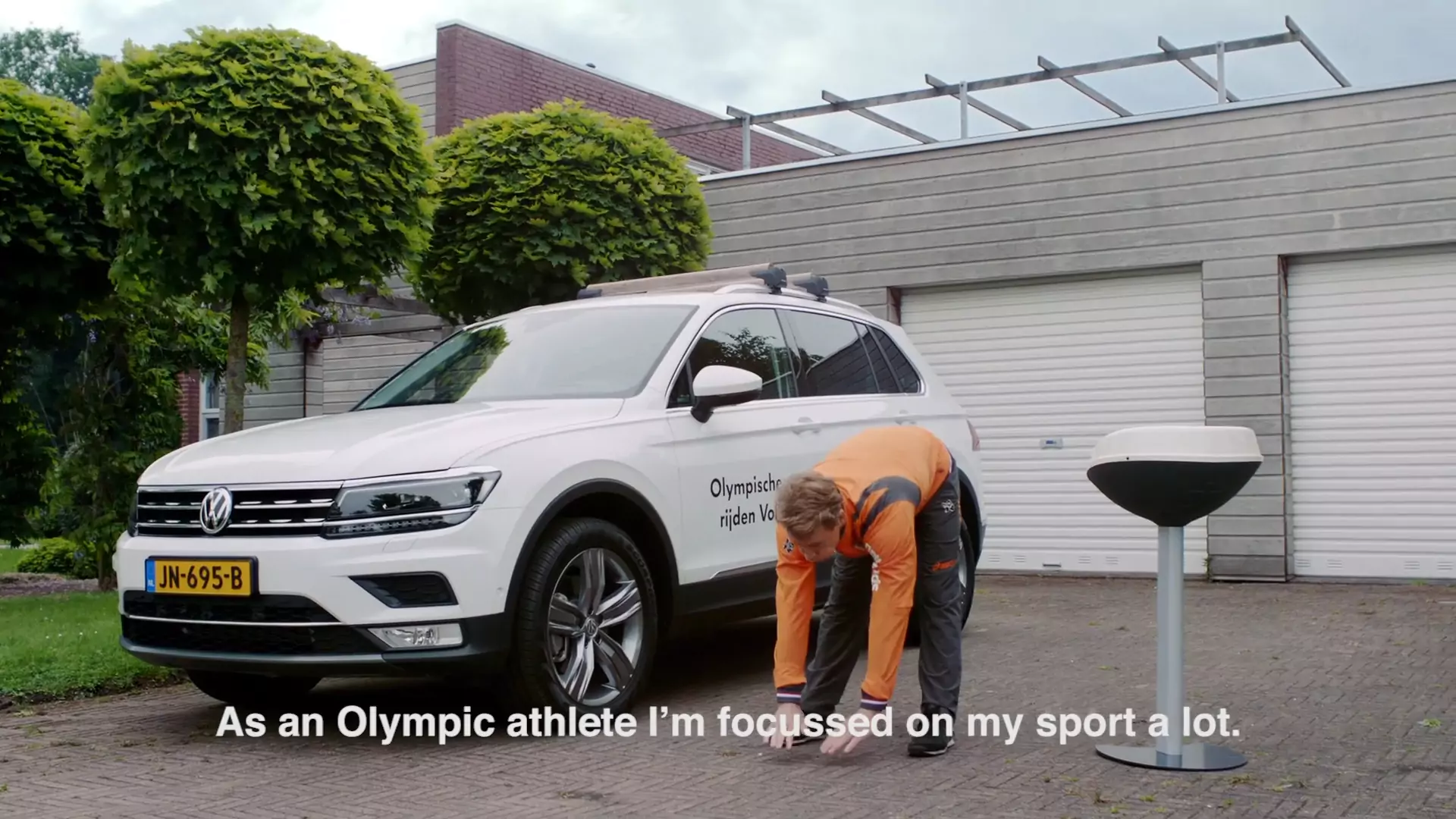 Epke Zonderland stretching next to the Tiguan in front of a row of garage doors