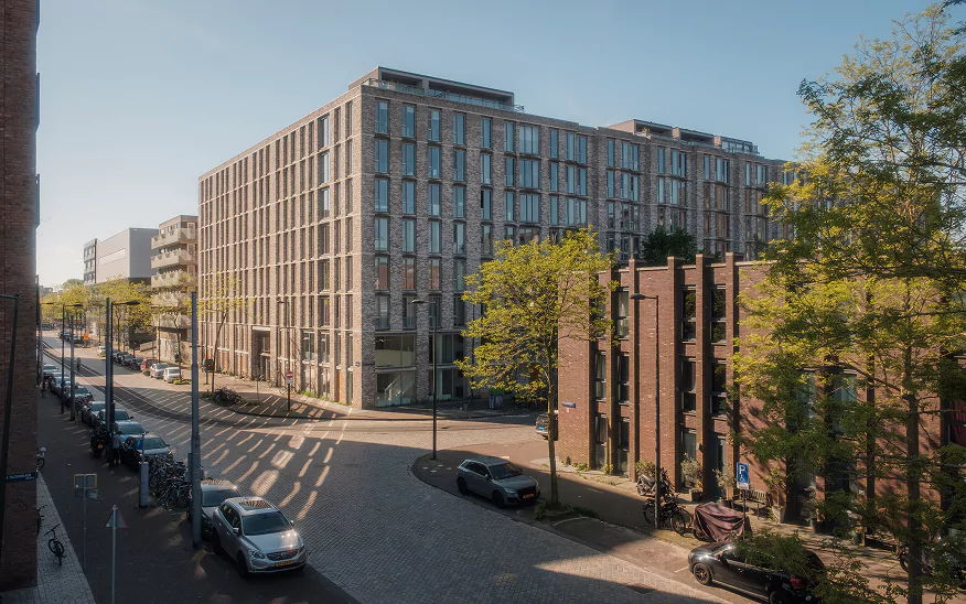 A wide street with parked cars in an Amsterdam neighbourhood